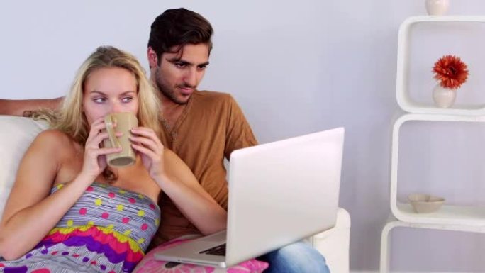 无聊的夫妇在沙发上看笔记本电脑