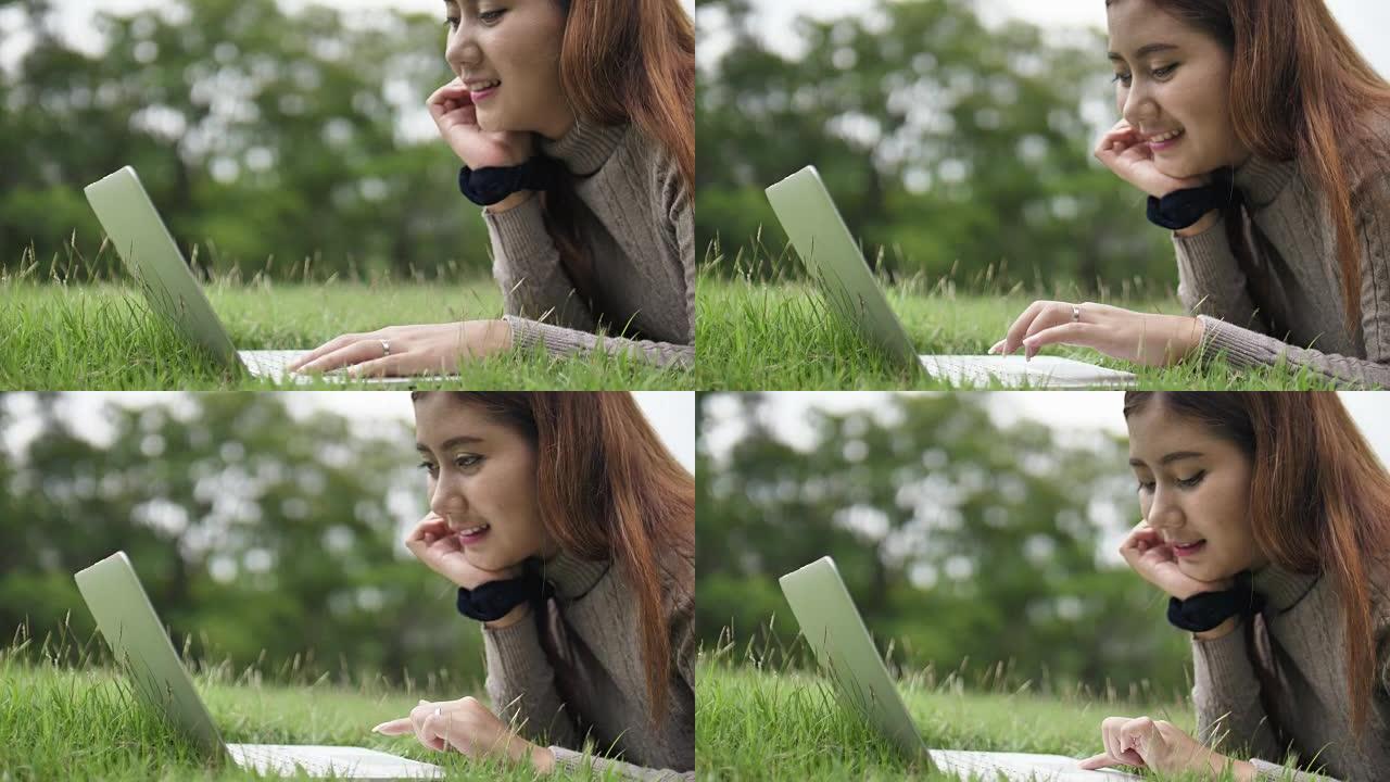 年轻女子在公园里用笔记本电脑打字