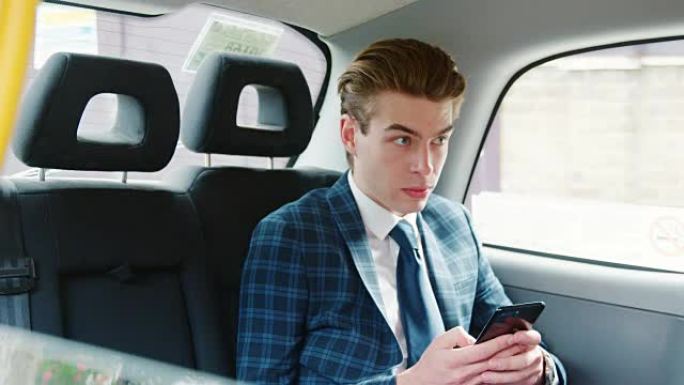 时髦的男人穿着西装在出租车上使用手机