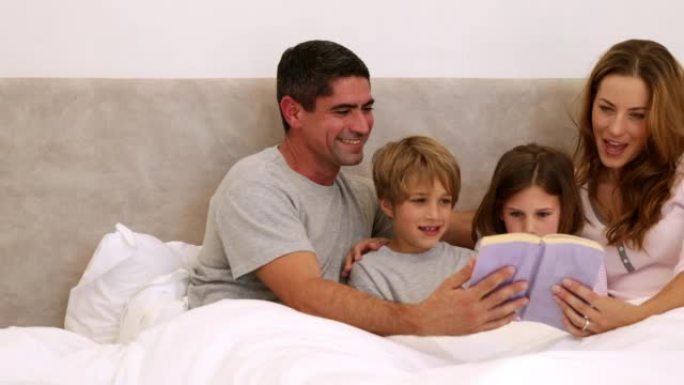 快乐的父母和孩子在床上一起阅读