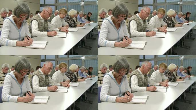 高清: 老年人在研讨会上写笔记