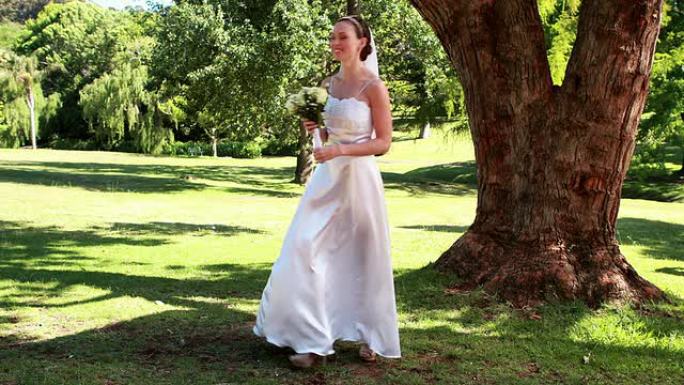 兴奋的新娘在公园里捧着花束