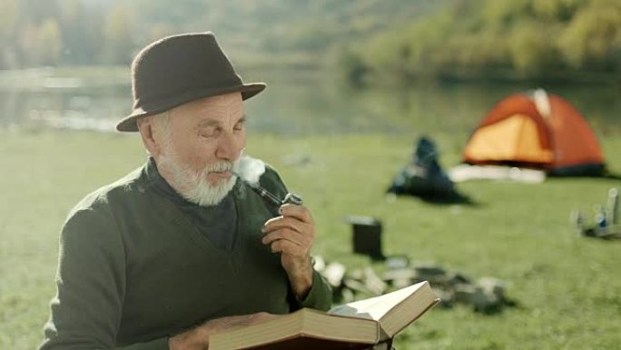 老人在湖边抽烟看书