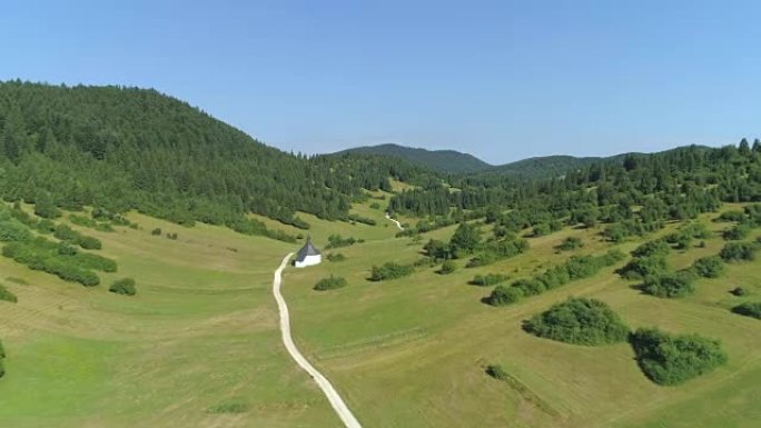 空中: 田园诗般的山谷乡间小路旁的草地上的小教堂