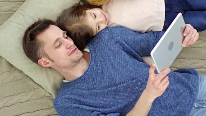 父亲和女儿躺在平板电脑上