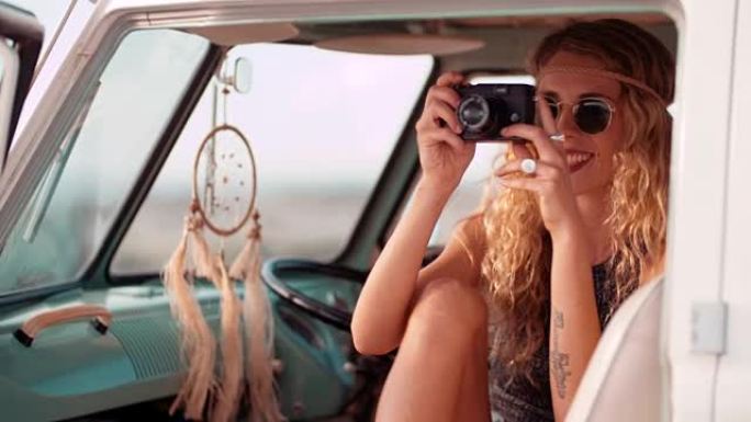 波西米亚时髦女孩坐在货车上拍摄公路旅行照片
