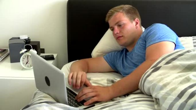 十几岁的男孩躺在床上，用笔记本电脑