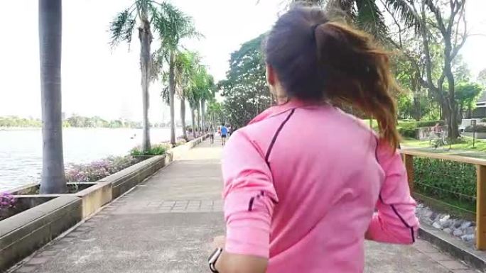 慢动作 -- 年轻的亚洲女人早上在人行道上跑步。年轻的体育亚洲女子在公园跑步。健身运动人群与健康生活