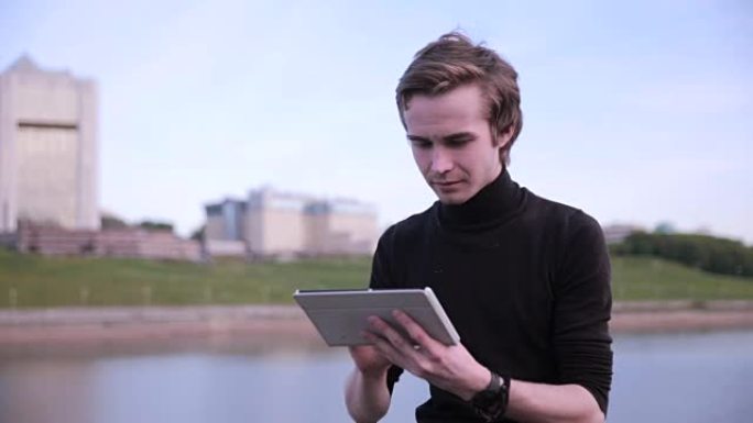 年轻人在城市湖附近的平板电脑上收到消息