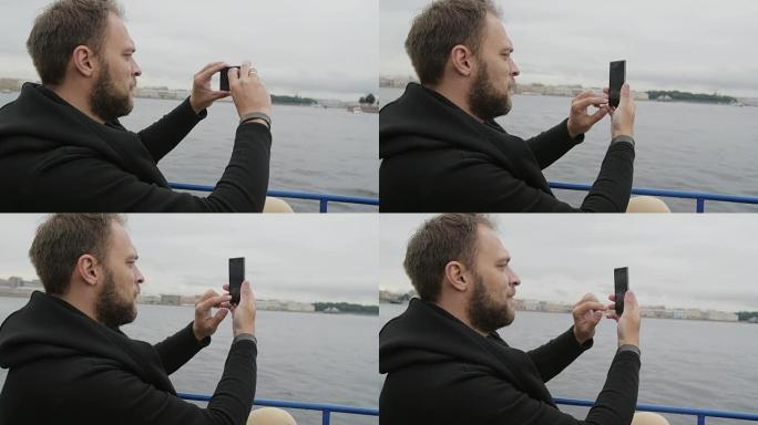 一个英俊的男人在俄罗斯圣彼得堡观光时拍照的侧景。男人使用智能手机，慢速