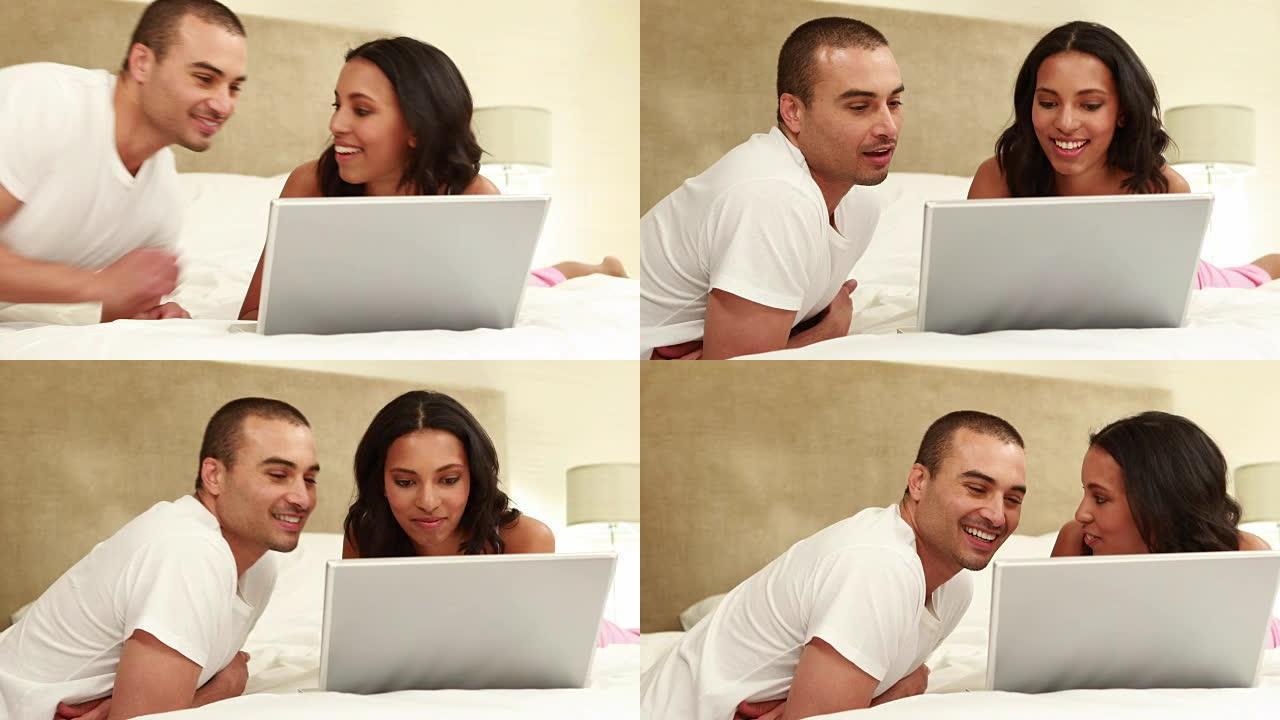 放松的夫妇在床上使用笔记本电脑