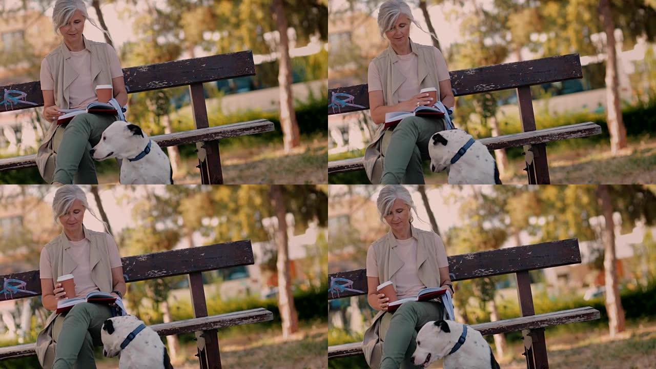 公园里有狗和咖啡阅读书的成熟女人