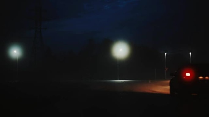 一辆汽车驶向大气黑暗的夜晚高速公路。美丽神秘的电影镜头。风景秀丽的天空。博克城市之光