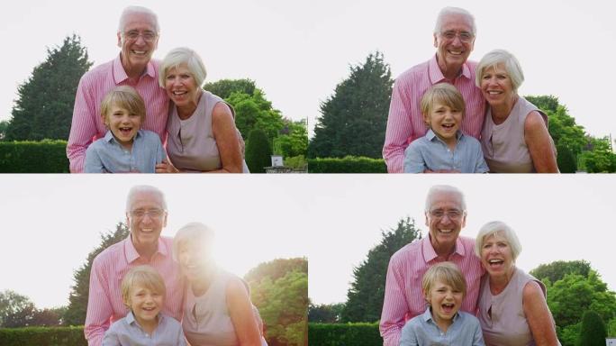 祖父母和孙子在花园里对着镜头微笑