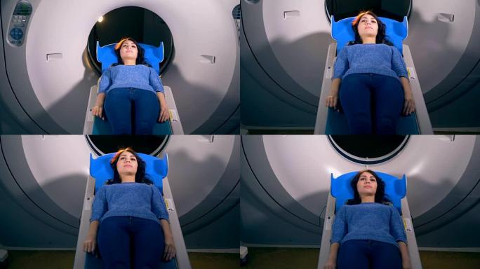 一个女人从CT扫描仪的打开环滑出。