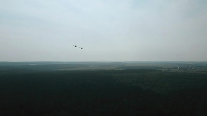 两架直升机近距离飞行的鸟瞰图。军用飞机编队飞越绿色森林到遥远的城市