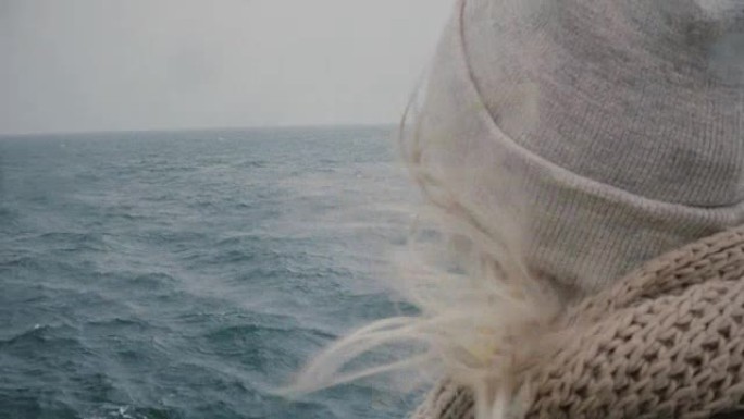 年轻金发女子在船上旅行的特写镜头。迷人的女性在大海和海浪上看，头发在风中挥舞