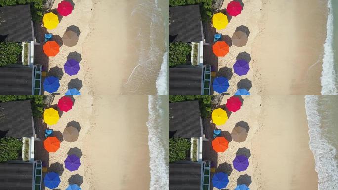 空中自上而下: 阳光明媚的沙滩上小屋前的彩色遮阳帘