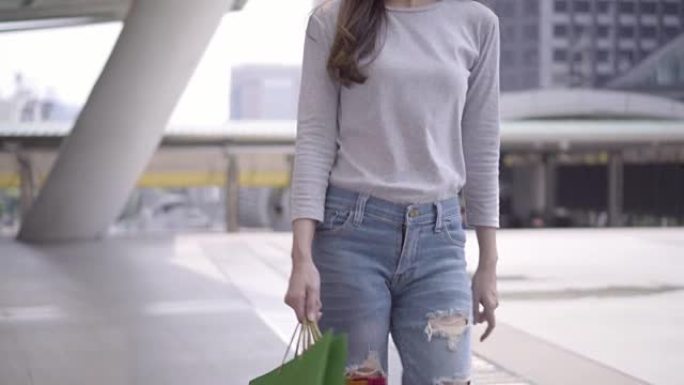 穿着时尚牛仔裤的女性带着购物袋散步