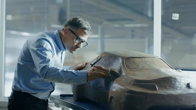 Rake首席汽车设计师用橡皮泥雕刻未来的汽车模型。他在一家大型汽车工厂的特殊工作室工作。