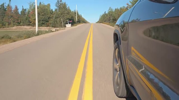 特写: 车辆沿着空旷的道路行驶，穿过广阔的加拿大荒野