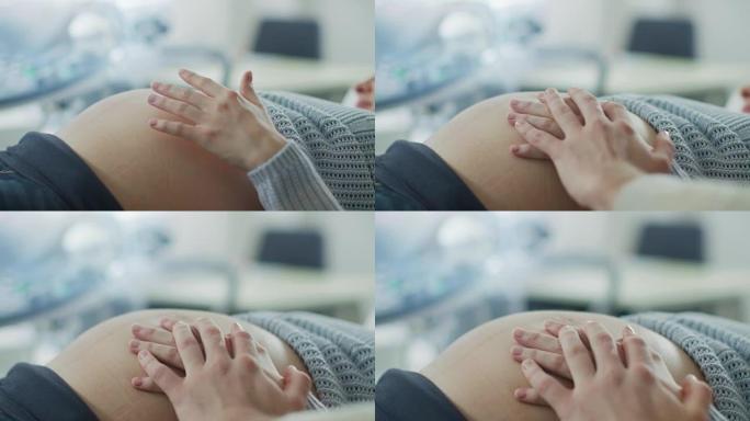 特写在孕妇的肚子上，她和丈夫仔细触摸它，试图感觉到婴儿是否踢。