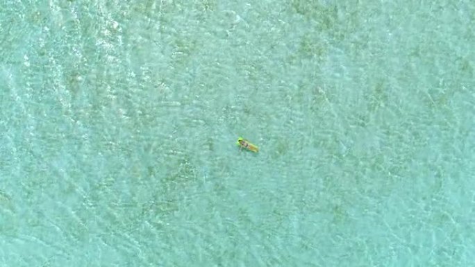 4k天线: 飞向躺在阳光明媚的波拉波拉岛美丽的海洋礁中间的绿色轻浮空气床床垫上的女人