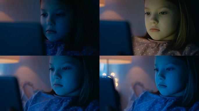 可爱的年轻女孩晚上躺在床上，用平板电脑照亮她的脸。