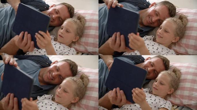 父亲和女儿躺在地板上使用数字平板电脑
