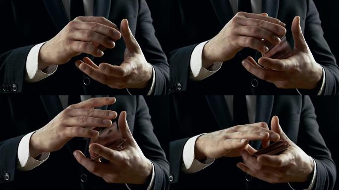 魔术师双手表演纸牌戏法的特写镜头。在空中投掷和捕捉卡片。背景是黑色的。慢动作。