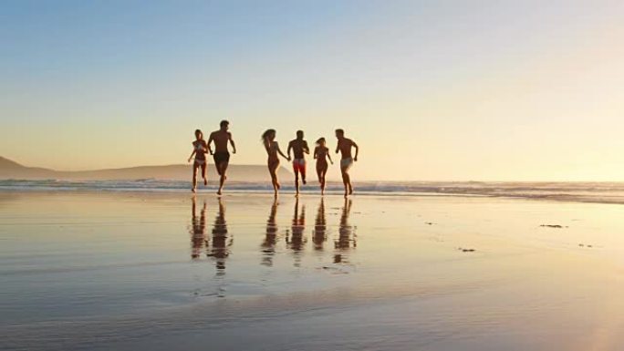 在海滩度假的日落时分，朋友在海浪中奔跑