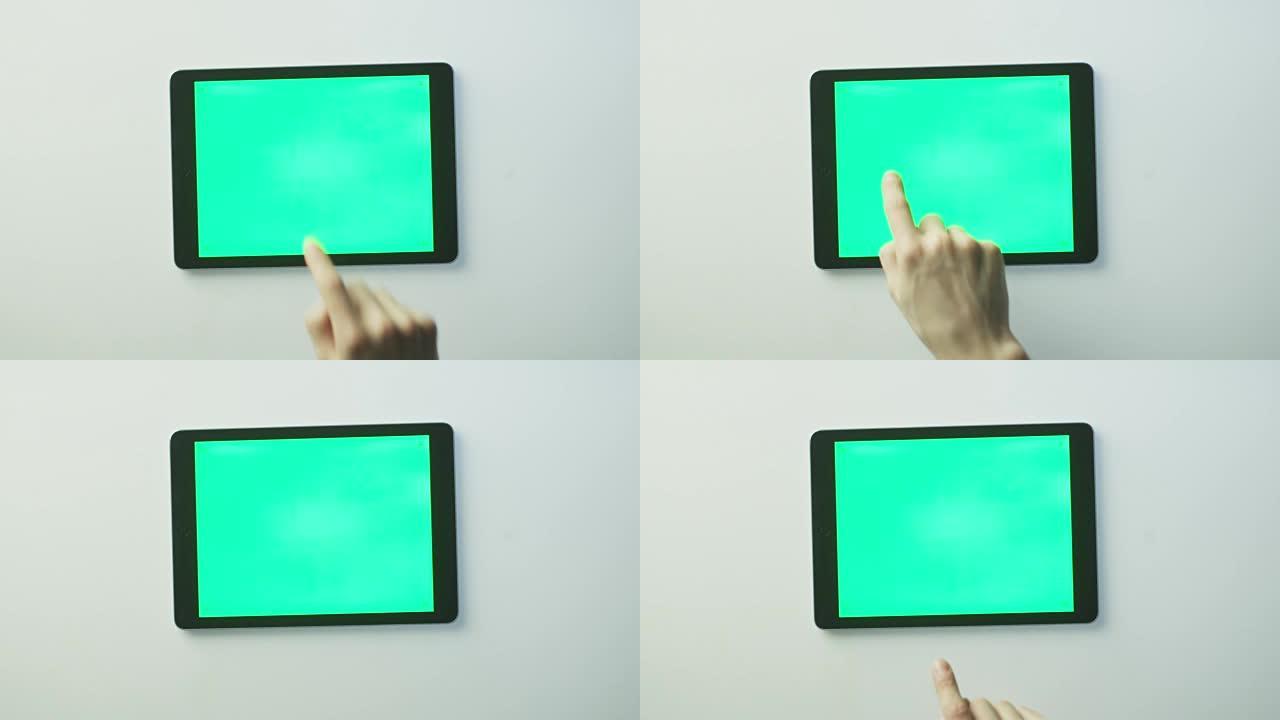 手正在将带有绿色屏幕的平板电脑放在白色桌子上，并开始使用它。非常适合使用模型。在红色电影摄影机上拍摄