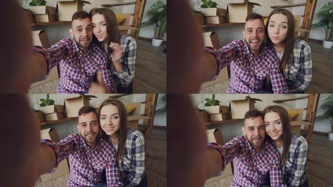 年轻人的观点镜头幸福的夫妇录制了关于一起搬进新房子，交谈和展示钥匙的视频。青春与重新定位概念。