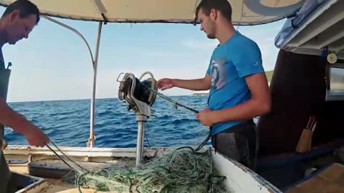 渔民从渔船上的网中取出龙虾和鱼