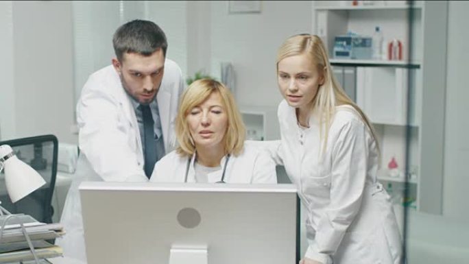 医务人员在使用个人计算机时讨论与工作相关的问题。男医生指着屏幕。