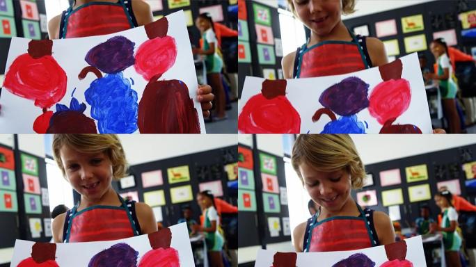 快乐的女孩在绘画课上展示她的画