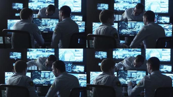 一群安全人员正在充满显示屏的黑暗监控室里进行工作对话。