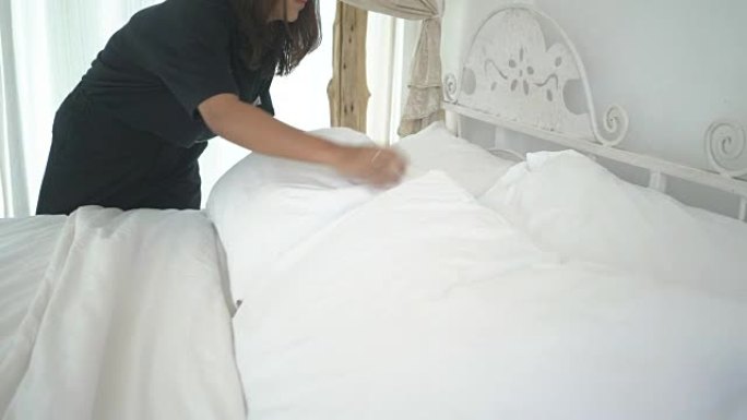 妇女在卧室里手工整理和清洁床