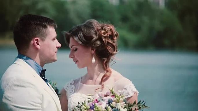 婚礼当天。美丽的夫妇享受他们的幸福站在码头上，接吻。婚纱，花束