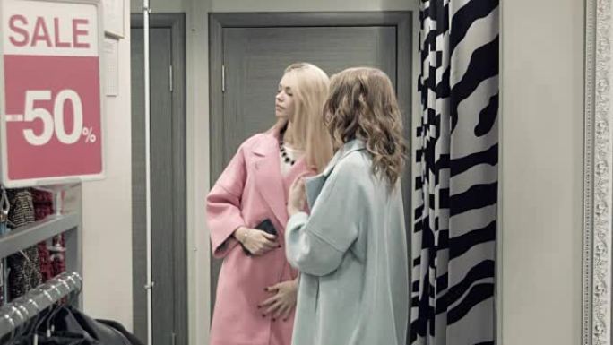 两个女孩在更衣室试穿外套