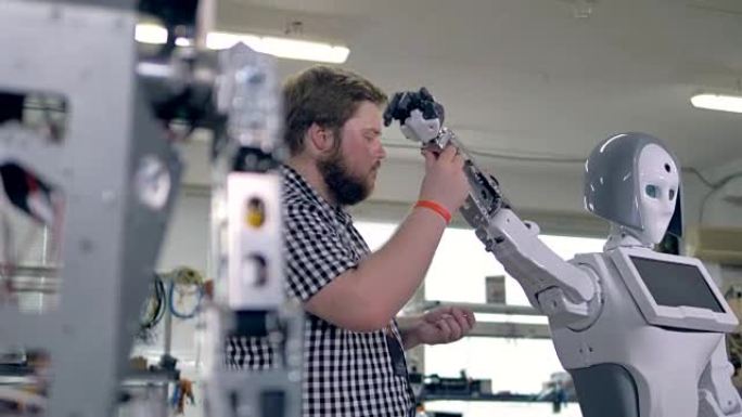 工程师抬起机器人的手臂，在其插槽中添加螺母。4K。