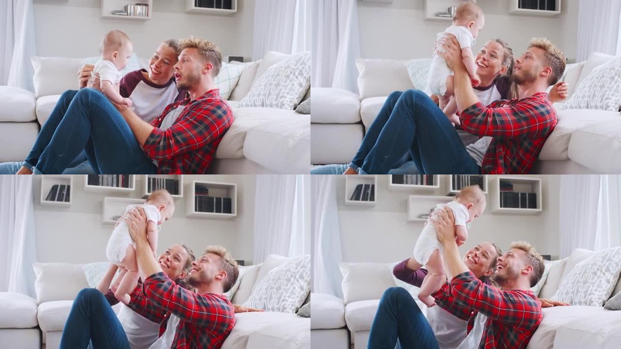 年轻的白人夫妇坐在家里和婴儿玩耍，侧视