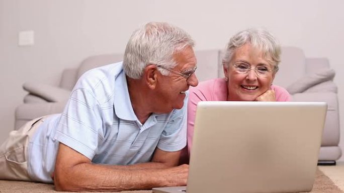 老年夫妇躺在地板上使用笔记本电脑