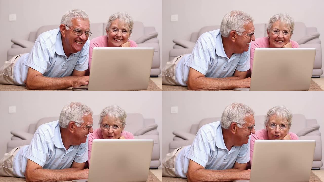 老年夫妇躺在地板上使用笔记本电脑