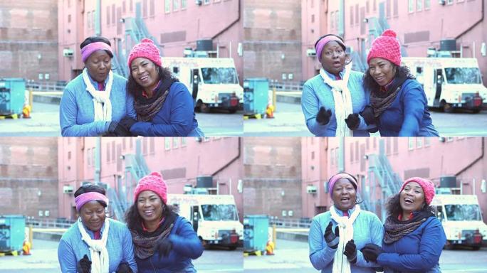 两名穿着暖和衣服的非裔美国妇女大笑