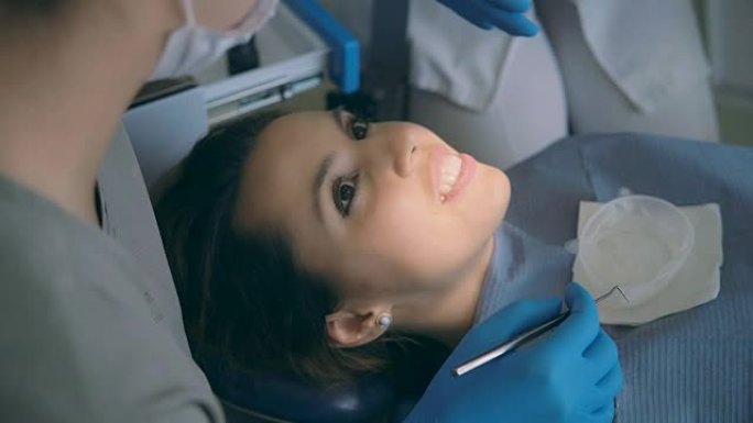 年轻女子坐在牙科椅上与医生交谈。女牙医建议时微笑和大笑