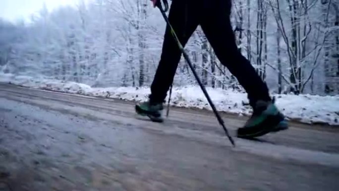 徒步旅行者的腿在白雪皑皑的森林旁行走