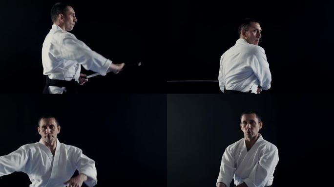 穿着传统武士Hakama衣服的合气道大师的侧视图将他的日本刀从刀鞘中取出并摆动。他在聚光灯下，黑暗包
