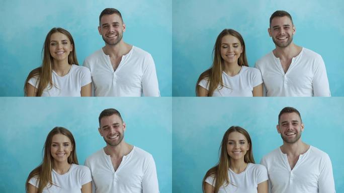 蓝色背景下年轻幸福的夫妇微笑着笑着对着镜头的肖像