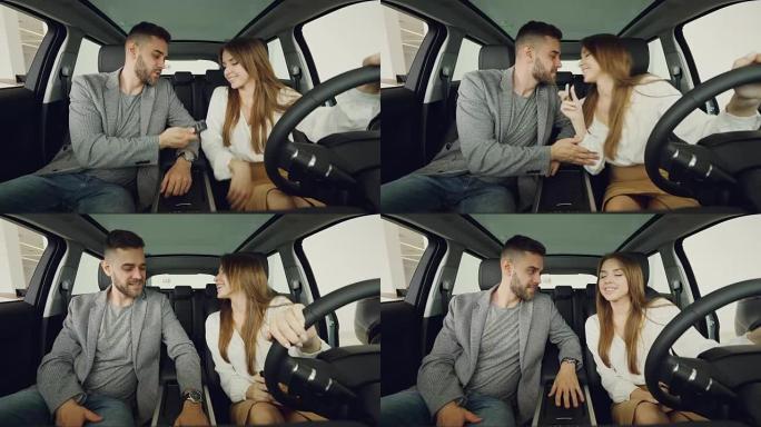 充满爱心的丈夫坐在装有漂亮内饰和真皮座椅的新车中时，将汽车钥匙交给了幸福的妻子。兴奋的女人正在亲吻他